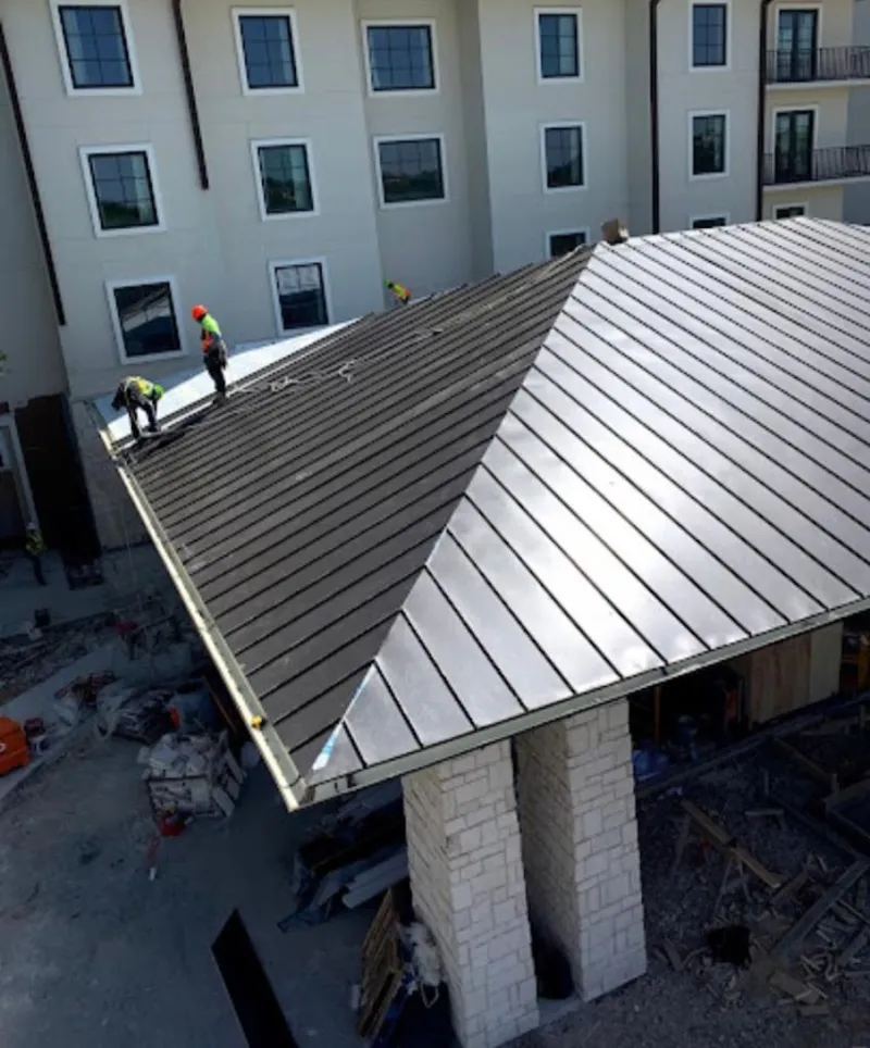 Crew installing standing seam metal roof panels on a commercial project in Wareham